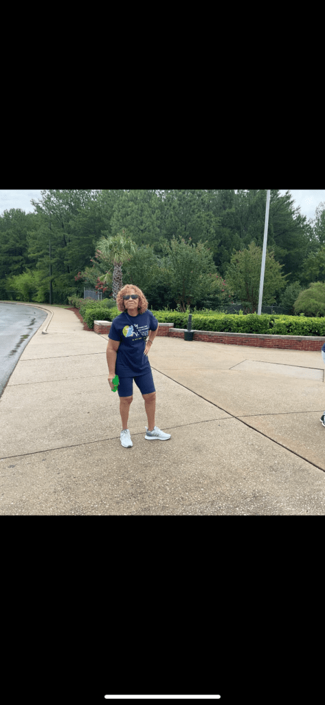 A Woman Wearing a Blue Shirt and a White Hat Stands Confidently on a Sidewalk